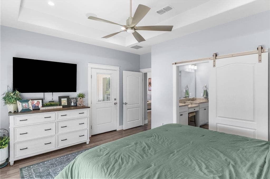 203 Splitrail Drive, Mabank, TX 75143 Tray ceiling with a multi-blade ceiling fan, wood-finish flooring, and white paneled sliding barn door