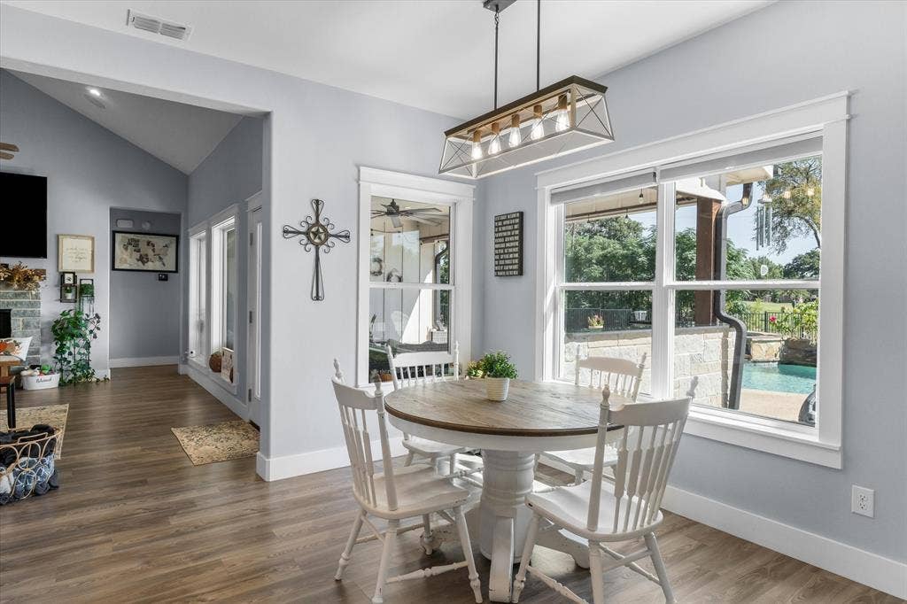 203 Splitrail Drive, Mabank, TX 75143 Dining area featuring wood-finish flooring, vaulted ceilings, multi-light rectangular pendant fixture, and large windows with outdoor pool exposure