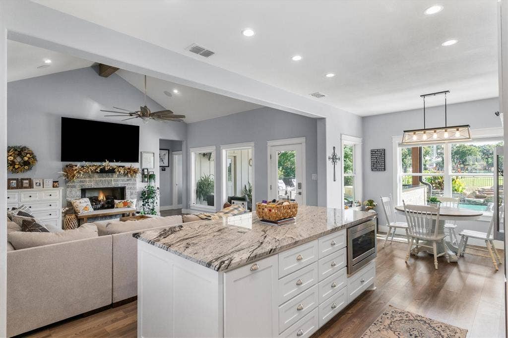 203 Splitrail Drive, Mabank, TX 75143 Open-concept kitchen and living area featuring a large center island with stone countertop, vaulted ceilings with recessed lighting, and a stone-surround fireplace