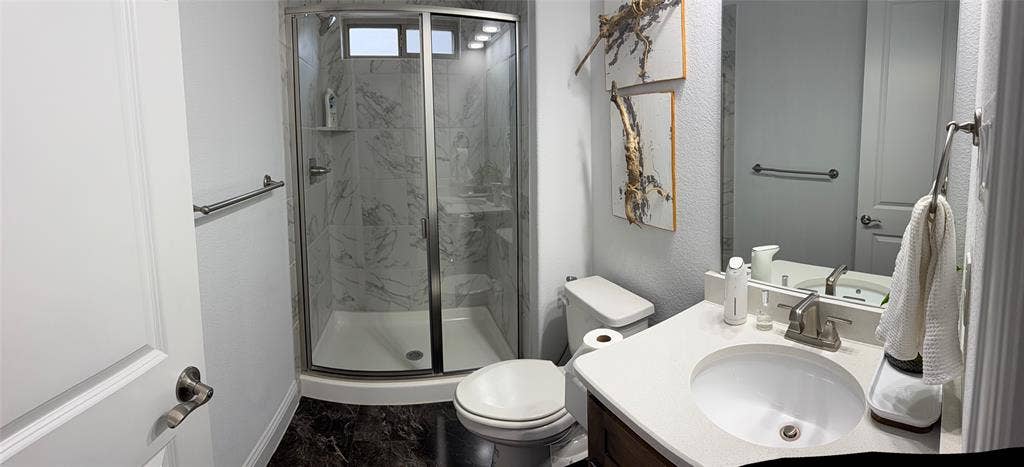 Bathroom featuring a walk-in shower with glass enclosure and surround tiling, vanity with a light-toned countertop, and integrated sink