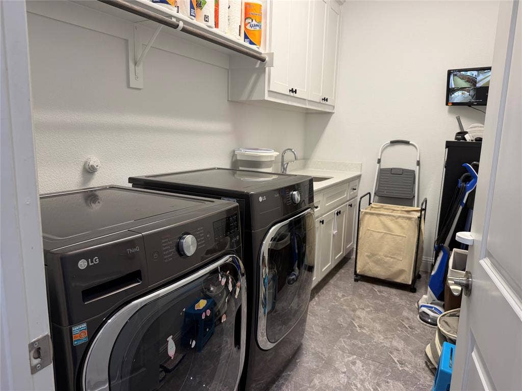 Laundry room featuring shaker-style white cabinetry, stone-finish countertops, integrated basin sink, overhead shelving, and tiled flooring