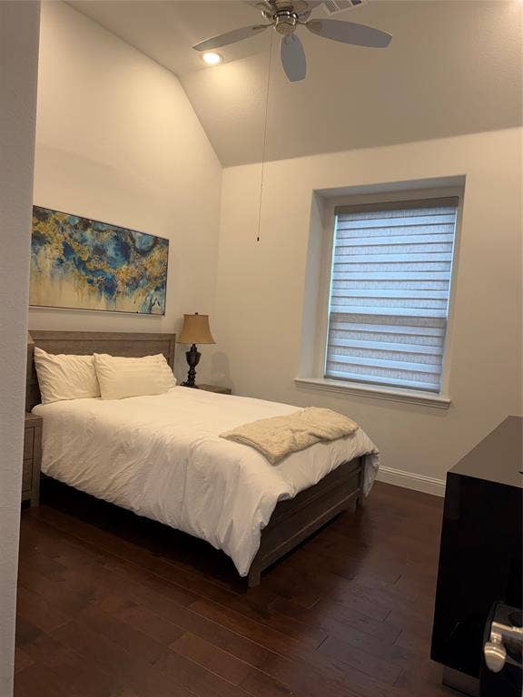 Vaulted ceiling with integrated recessed lighting and a ceiling fan, dark wood-finish flooring, and a multi-tiered window treatment