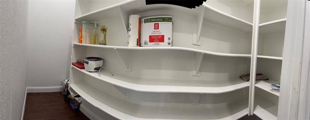 Storage pantry featuring white custom curved shelving and wood-finish flooring