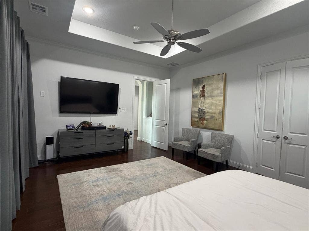 Tray ceiling featuring recessed lighting and a brushed-nickel ceiling fan, accompanied by wood-finish flooring and solid-core paneled doors
