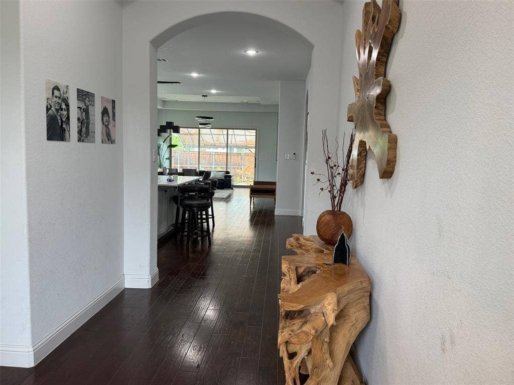 Interior hallway featuring arched architectural detail, dark wood-finish flooring, and recessed ceiling lighting