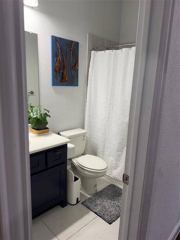 Dark-finish vanity cabinetry with a solid-surface countertop, rectangular wall-mounted mirror, and tile flooring