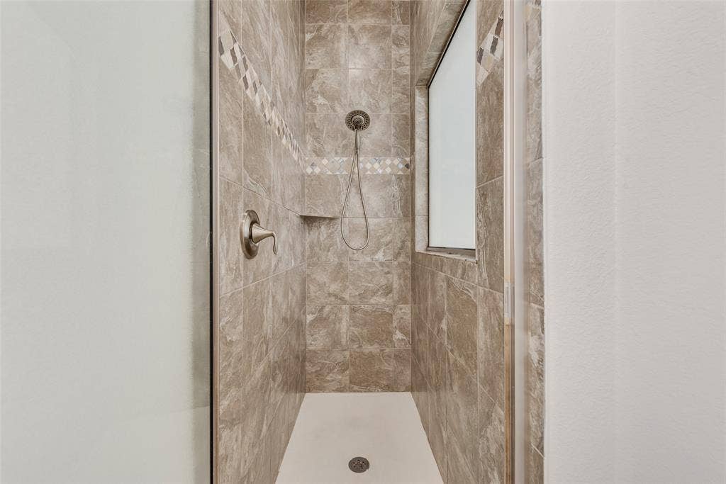 Primary bathroom shower with gorgeous tile and frosted window.