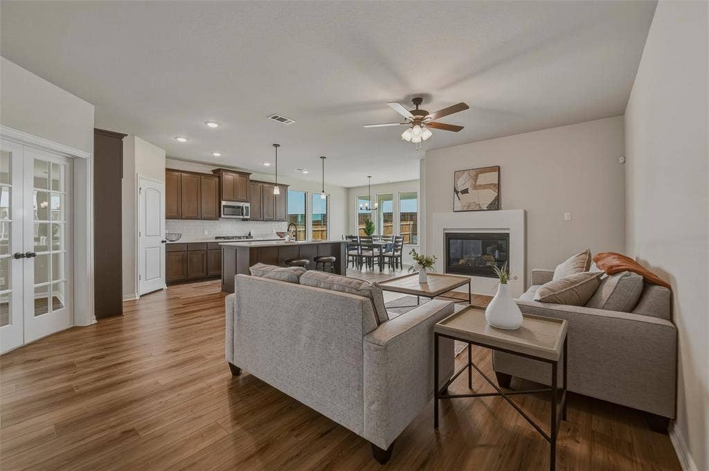 Open-concept living space featuring wood-finish flooring, a fireplace, and a ceiling fan