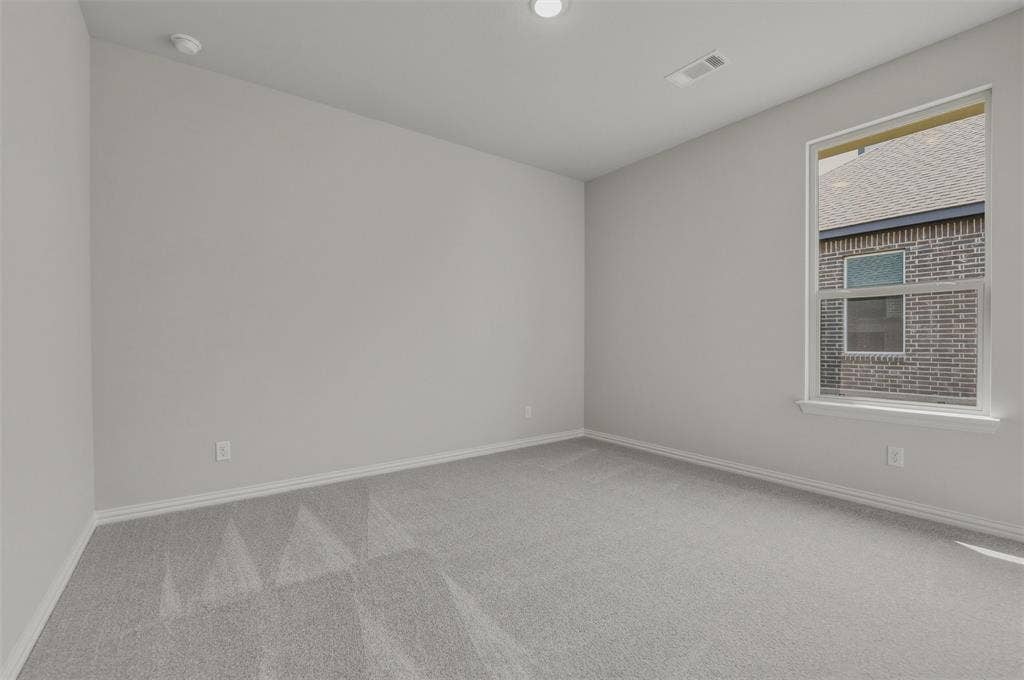 Bright secondary bedroom featuring neutral wall finishes, recessed ceiling lighting, carpet flooring, and a large window with natural light and brick exterior views