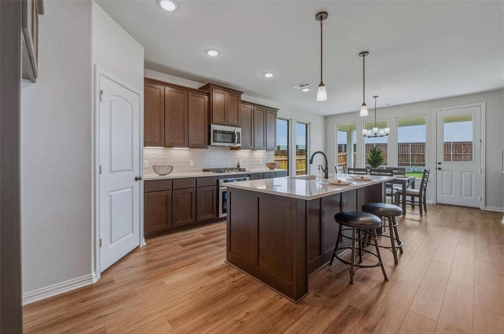 Kitchen featuring wood-finish flooring, dark wood cabinetry, a center island with countertop, and recessed lighting