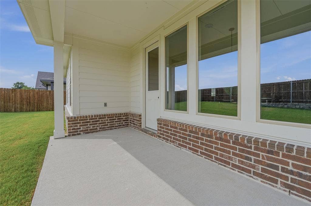 Covered outdoor patio with a concrete surface, white siding, and brick accent detailing