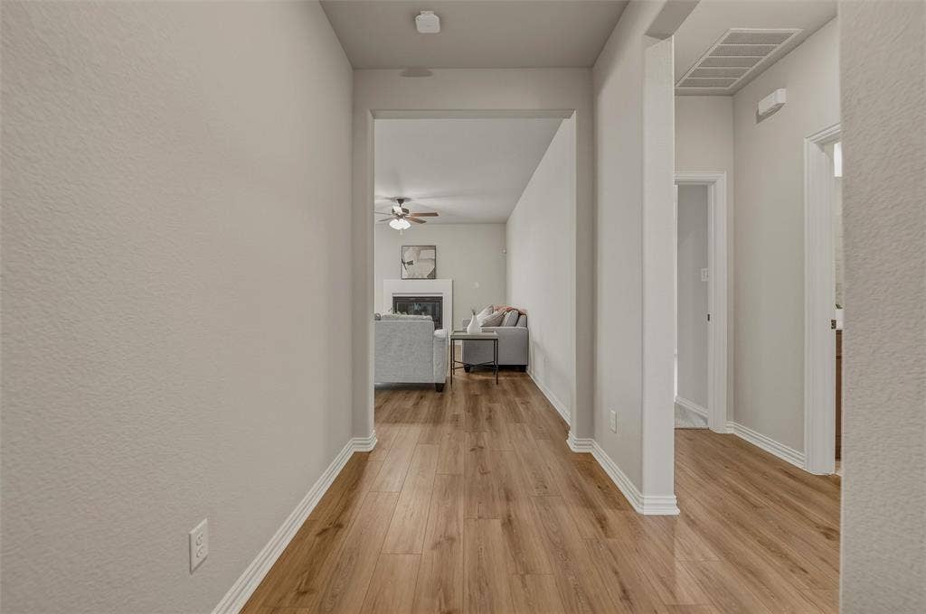 Light wood-finish flooring extending through the hallway and living area