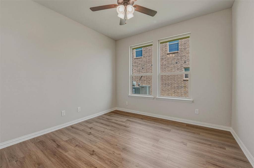 Wood-finish flooring, white trim, recessed windows, ceiling fan with integrated lighting