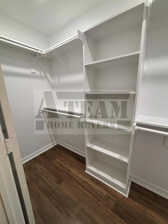 Walk-in closet featuring white built-in shelving, dual-tier hanging rods, and wood-finish flooring