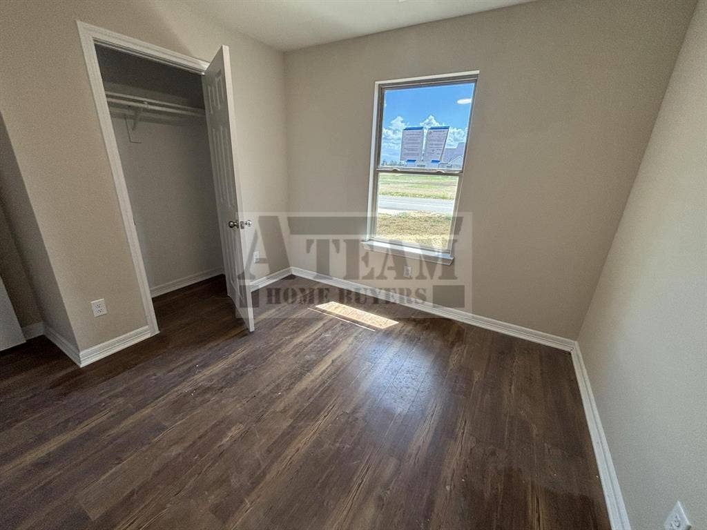 Interior room featuring wood-finish flooring, neutral wall paint, and a single-panel window