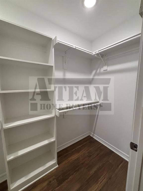 Walk-in closet featuring built-in white shelving, custom hanging rods, recessed lighting, and wood-finish flooring
