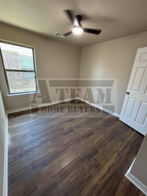 Room featuring wood-finish flooring, a neutral paint palette, a multi-pane window, and a ceiling-mounted light fixture with a fan