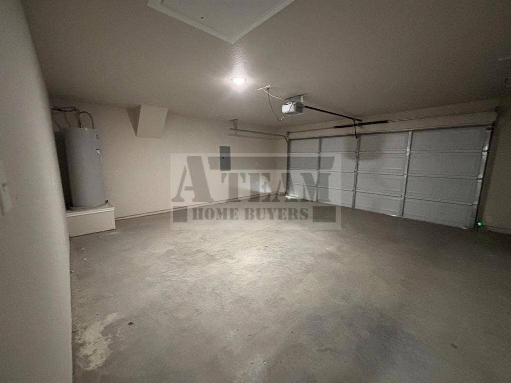 Attached garage featuring a multi-panel roll-up door, concrete flooring, and ceiling-mounted automatic door opener
