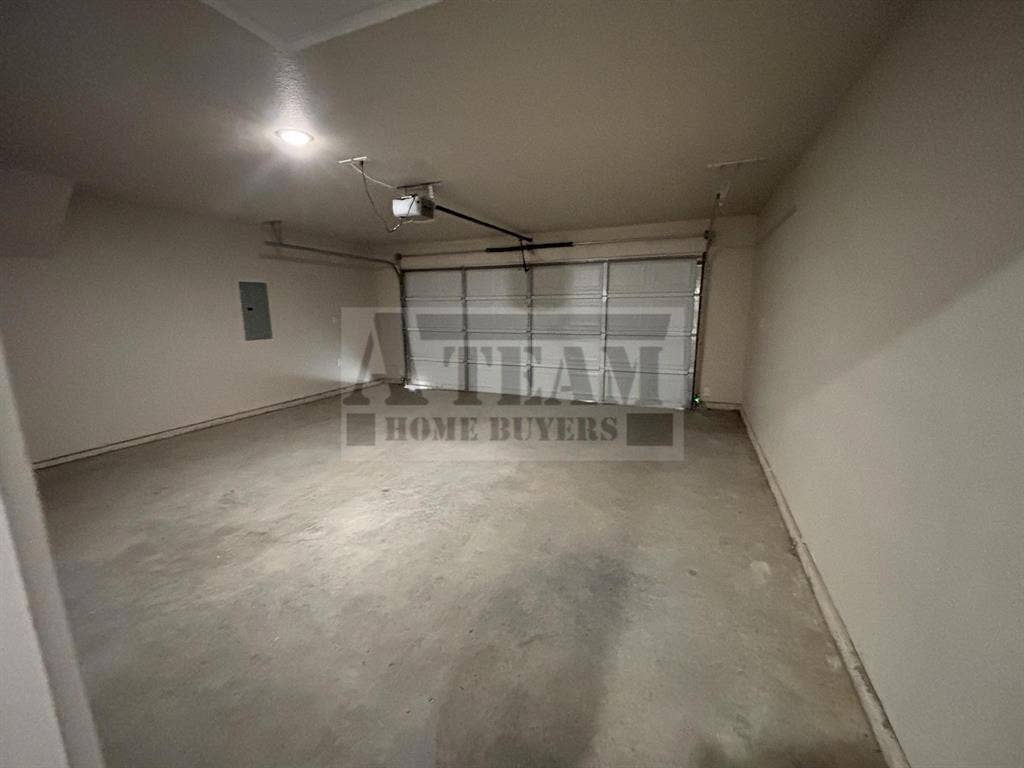 Multi-car garage featuring a concrete floor, sectional overhead door, automated door opener, and interior electrical service panel