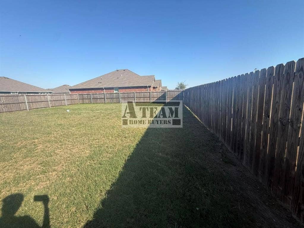 Backyard featuring a grass lawn and a full-perimeter wood privacy fence