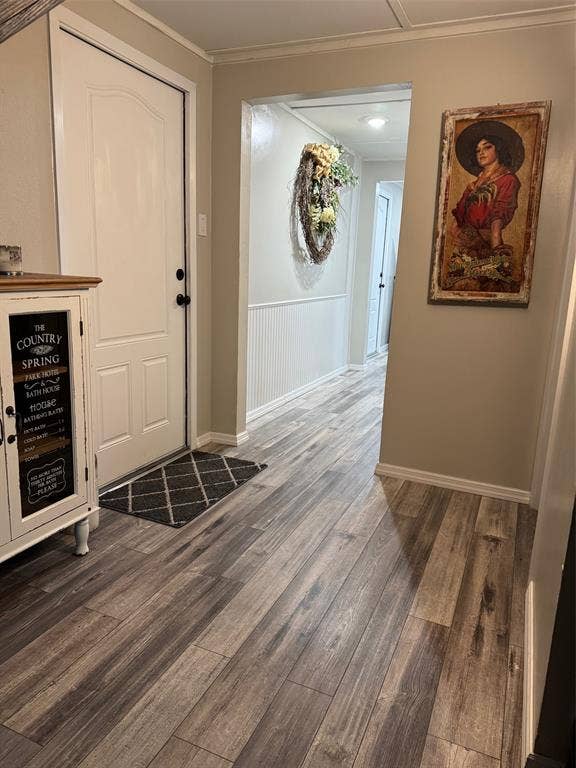 Entryway with dark wood-style flooring and ornamental molding