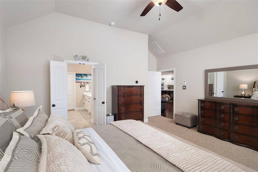 Vaulted ceilings, neutral wall tones, carpeted flooring, and a ceiling fan with integrated lighting