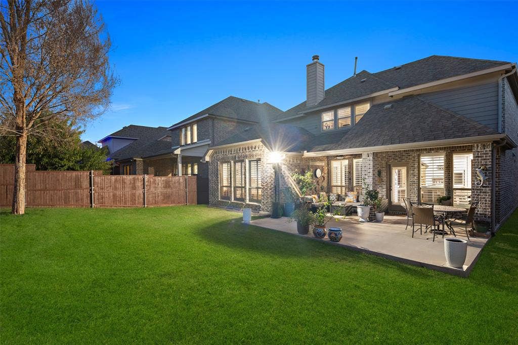 Brick and siding exterior featuring a concrete patio, wood fencing, and a manicured lawn