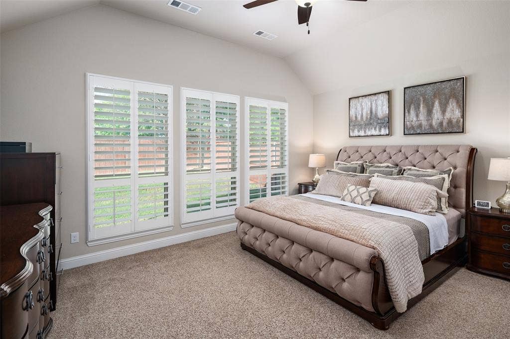 Vaulted ceiling, carpeting, and plantation shutters featuring triple-pane windows