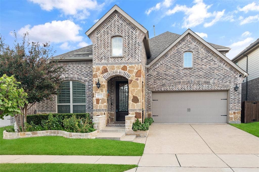 Multi-gabled brick exterior featuring decorative herringbone masonry, natural stone accents, arched entryway, and attached garage