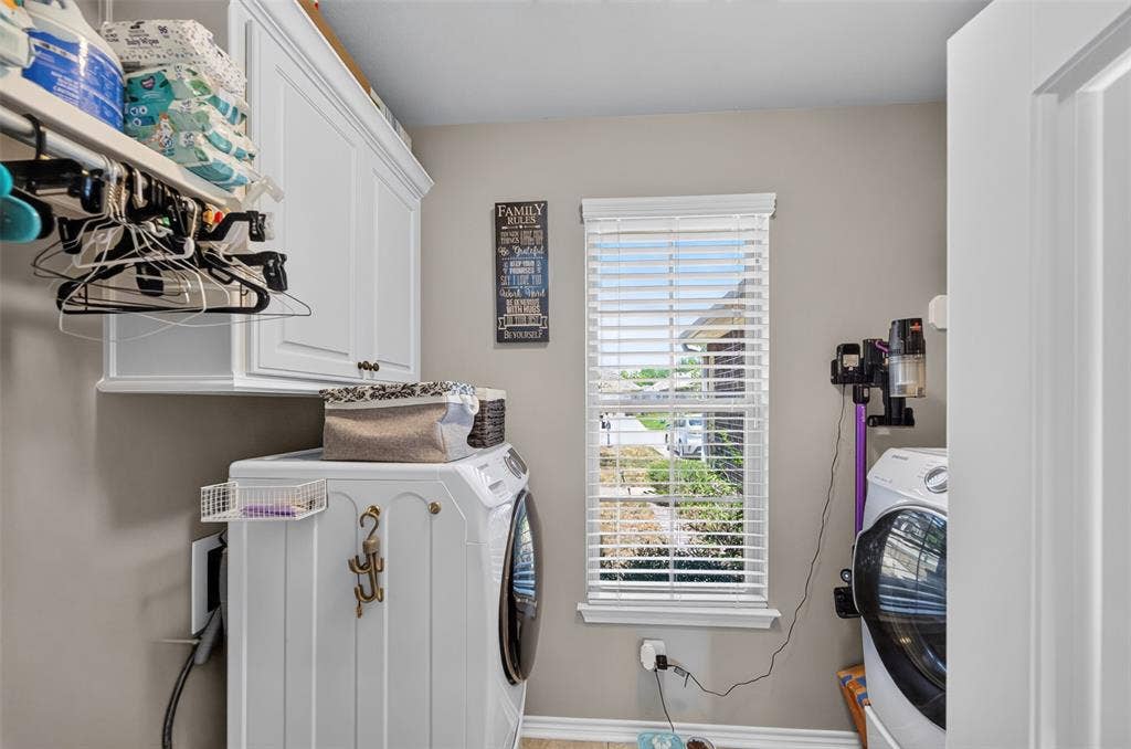 Utility room featuring white shaker-style cabinetry, overhead shelving with a built-in hanging rod, and a central window with horizontal blinds