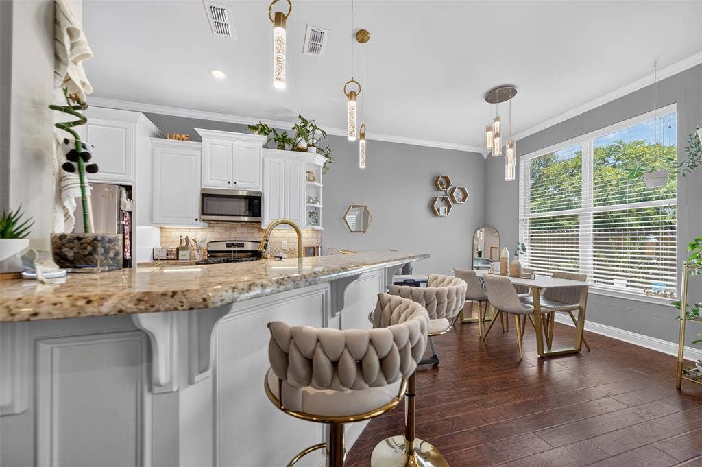 Kitchen featuring white cabinetry, stone countertops, wood-finish flooring, metal pendant lighting, and a multi-pane window
