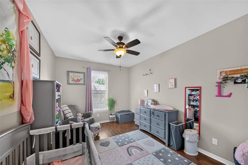 Neutral-toned bedroom featuring wood-finish flooring, a central ceiling fan with an integrated light fixture, and a single-pane window