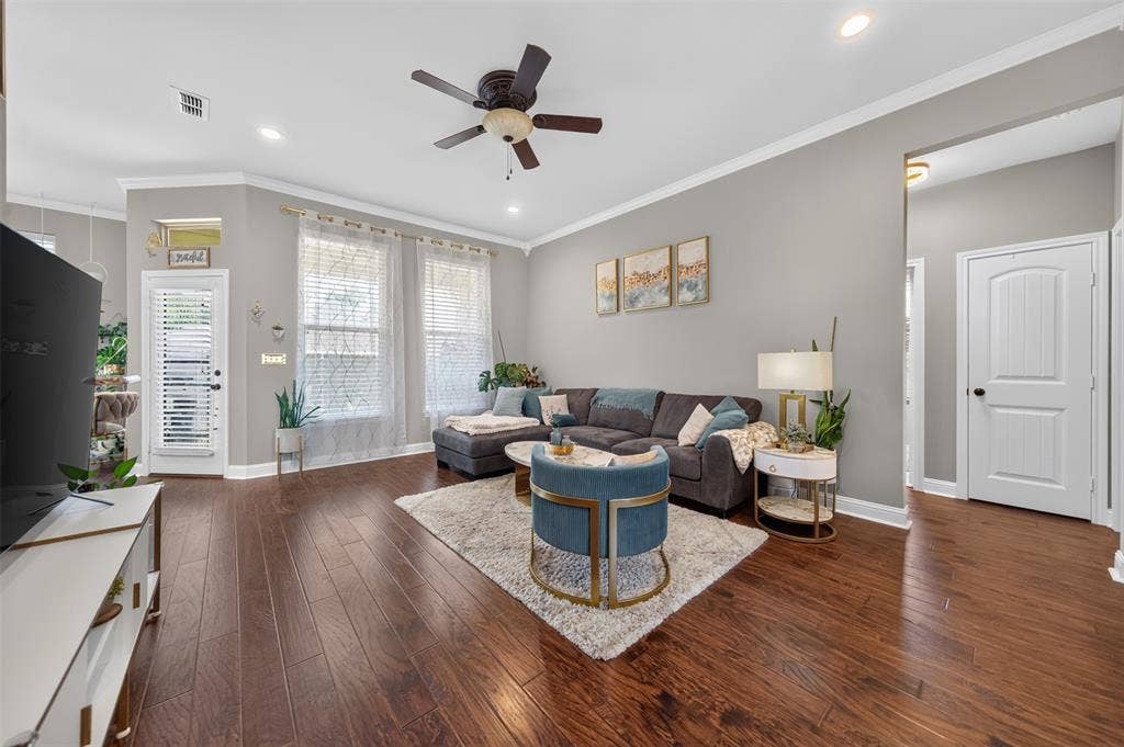 Wood-finish flooring, recessed lighting, crown molding, multi-pane windows with grid detailing, and a ceiling fan