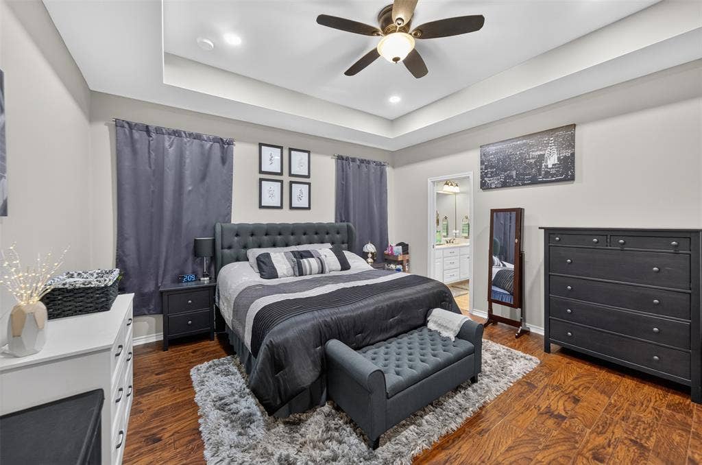 Tray ceiling with recessed lighting, integrated ceiling fan, and wood-finish flooring