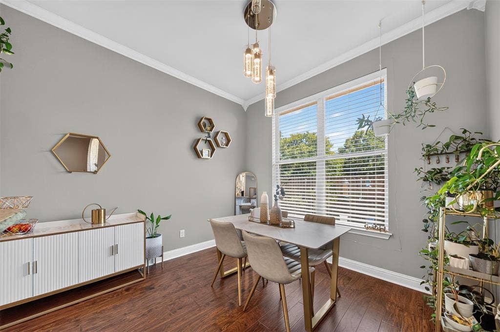 Dining area featuring wood-finish flooring, crown molding, a large multi-pane window, and a contemporary multi-pendant light fixture