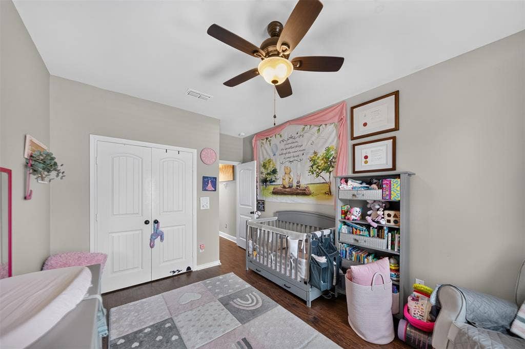 Room featuring wood-finish flooring, double-panel interior doors, and a ceiling fan with integrated lighting