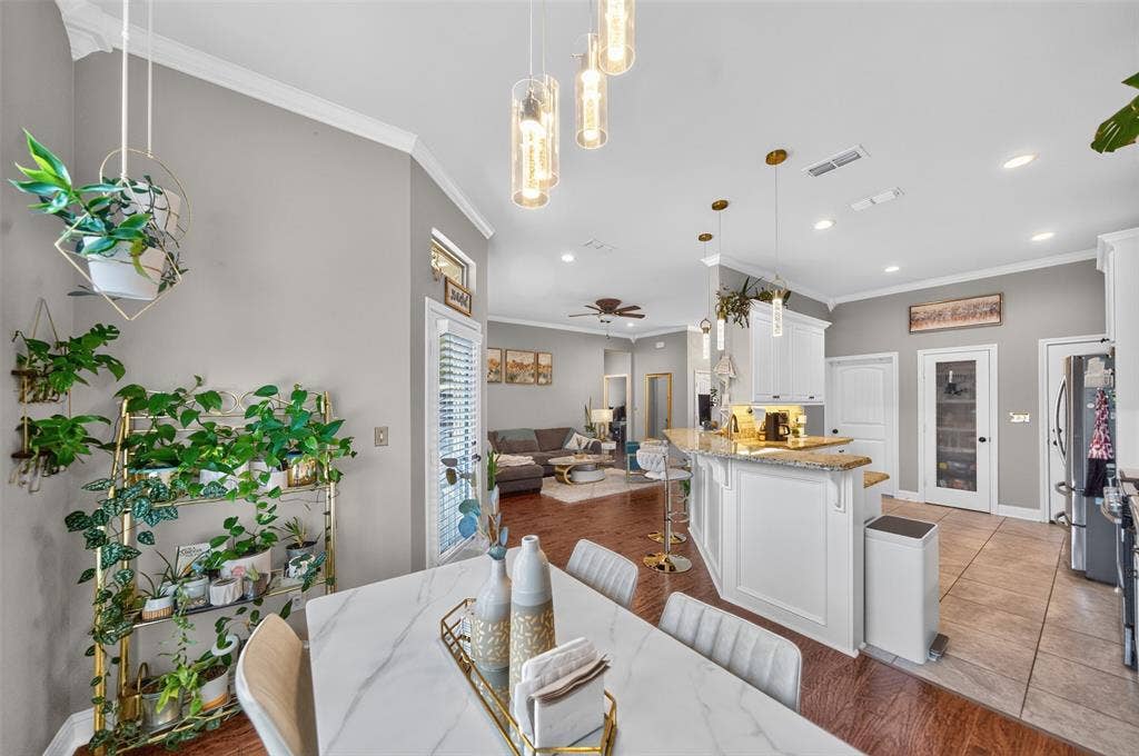Kitchen featuring white cabinetry, stone-finish countertops, tile flooring, and pendant lighting, with adjacent wood-finish flooring