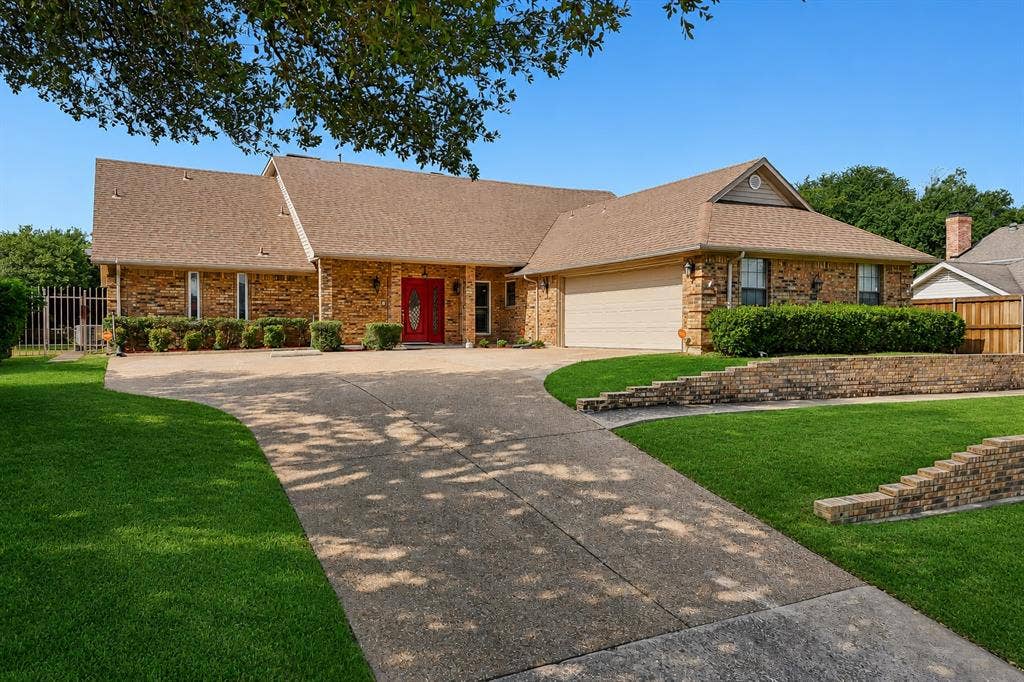 4008 Fairlakes Drive, Dallas, TX 75228 Brick-clad exterior with a red double-door entry, a two-car garage, and a concrete driveway