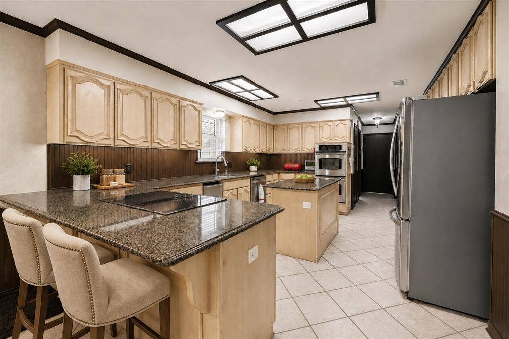 4008 Fairlakes Drive, Dallas, TX 75228 Kitchen featuring light-toned cabinetry, granite-finish countertops, stainless steel appliances, a center island, and tile flooring
