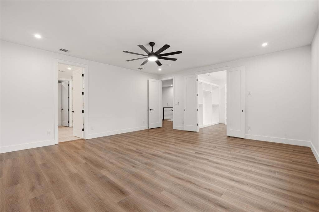 Wood-finish flooring, recessed lighting, matte black ceiling fan, and multi-panel interior doors