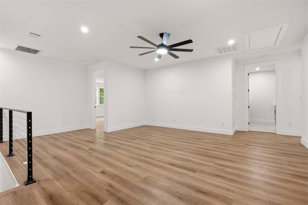 Open-concept interior featuring wood-finish flooring, recessed lighting, a modern ceiling fan with integrated lighting, and a cable-style staircase railing