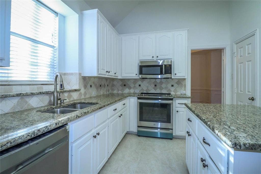 504 Renfro Court, Irving, TX 75063 Kitchen featuring white cabinetry, stone-surface countertops, diamond-pattern tile backsplash, stainless steel appliances, and a double-basin undermount sink