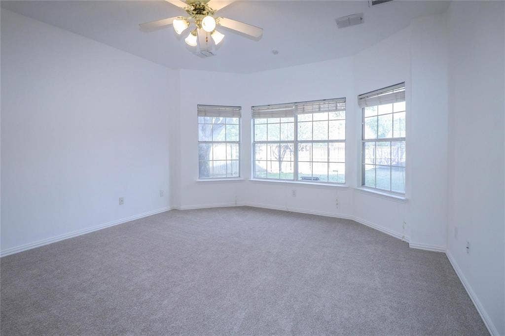 504 Renfro Court, Irving, TX 75063 Neutral-toned wall-to-wall carpeting, bay window configuration, multi-pane windows with fitted blinds, and a ceiling-mounted lighting fixture with an integrated fan
