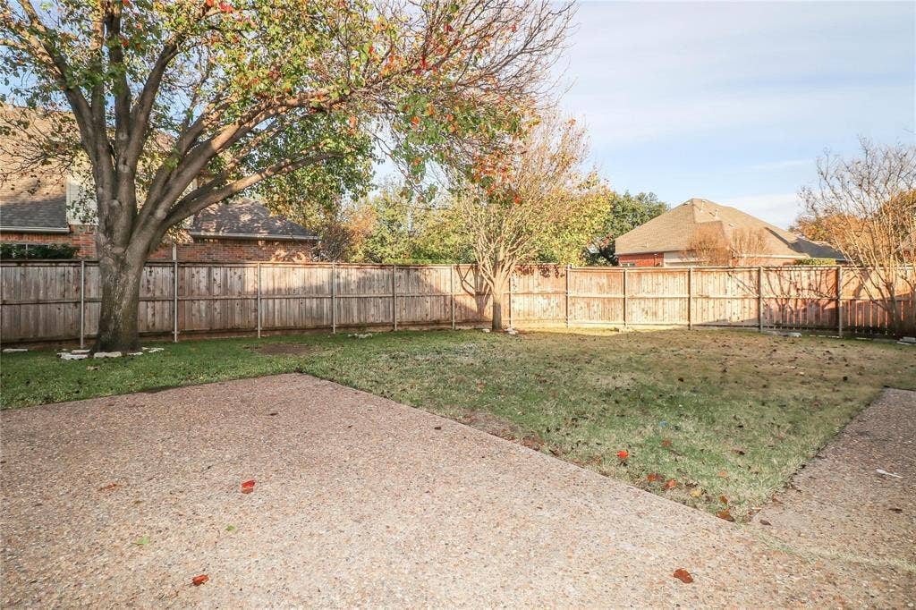 504 Renfro Court, Irving, TX 75063 Backyard featuring a concrete patio, grass lawn, wood privacy fencing, and mature trees
