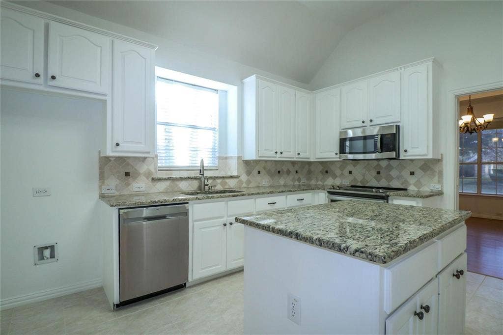 504 Renfro Court, Irving, TX 75063 Kitchen featuring white shaker-style cabinetry, stone countertops, stainless steel appliances, a central island, and a tile backsplash with diamond-pattern accents