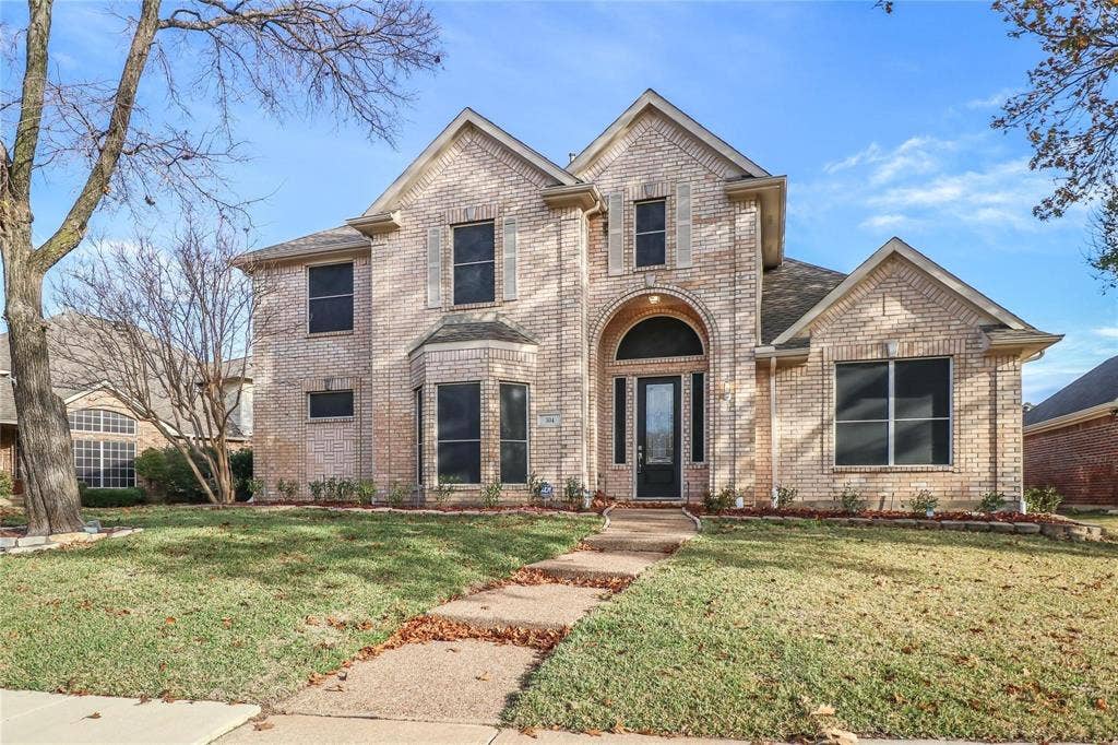 504 Renfro Court, Irving, TX 75063 Two-story brick exterior featuring a multi-gabled roofline, an arched entryway, decorative shutters, and a covered front porch