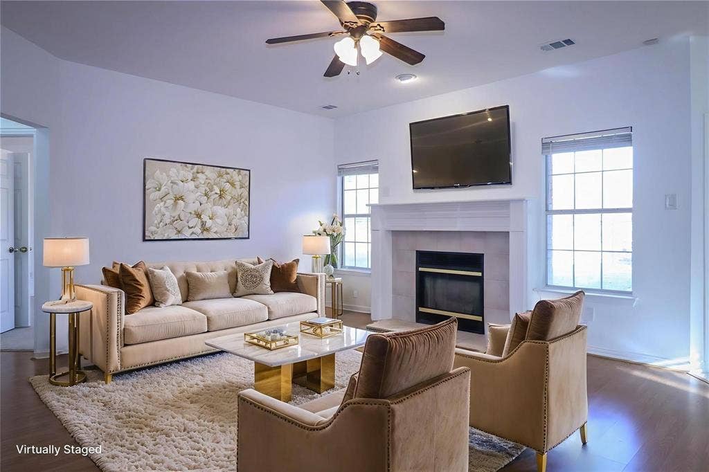 504 Renfro Court, Irving, TX 75063 Living area featuring a fireplace with a white mantel and tile surround, large windows, wood-finish flooring, and a ceiling fan with integrated lighting