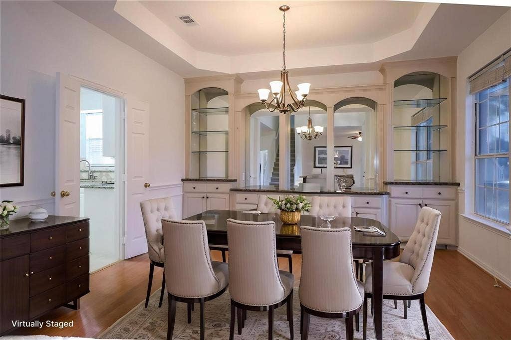 504 Renfro Court, Irving, TX 75063 Tray ceiling with central chandelier, built-in cabinetry featuring arched glass shelving, and wood-finish flooring