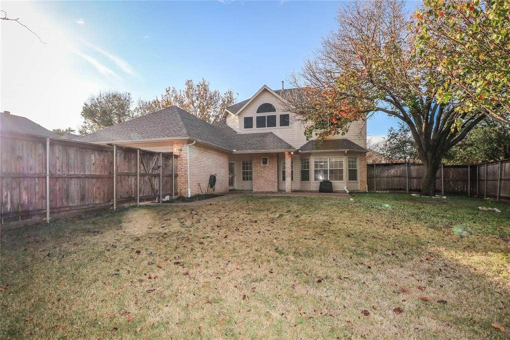 504 Renfro Court, Irving, TX 75063 Exterior elevation featuring a brick and siding facade, a multi-gabled roofline, an arched window, and an enclosed backyard with a wood privacy fence