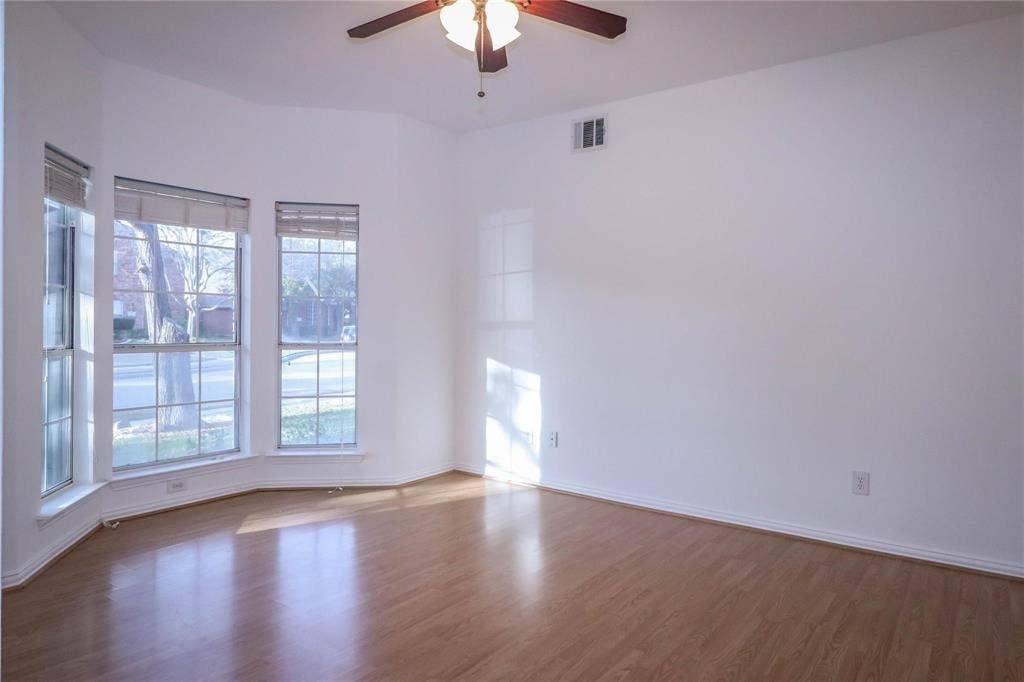 504 Renfro Court, Irving, TX 75063 Room featuring wood-finish flooring, a bay window configuration, and an attached ceiling fan with a light fixture
